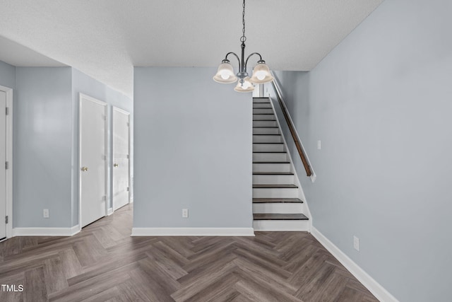 stairway featuring a notable chandelier, baseboards, and a textured ceiling