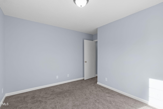 carpeted empty room featuring baseboards