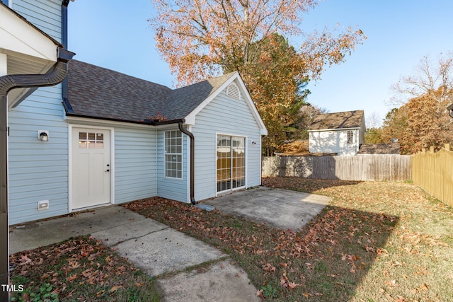 exterior space with a shingled roof, a fenced backyard, and a patio