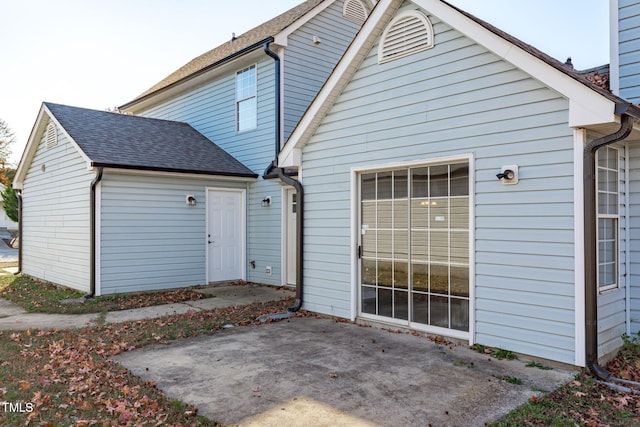 rear view of property with a shingled roof and a patio