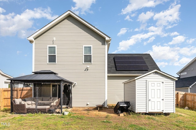 rear view of property with roof mounted solar panels, a shed, a gazebo, an outdoor living space, and an outdoor structure