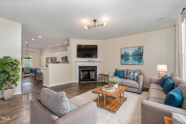 living room featuring wood finished floors, a chandelier, recessed lighting, baseboards, and a fireplace