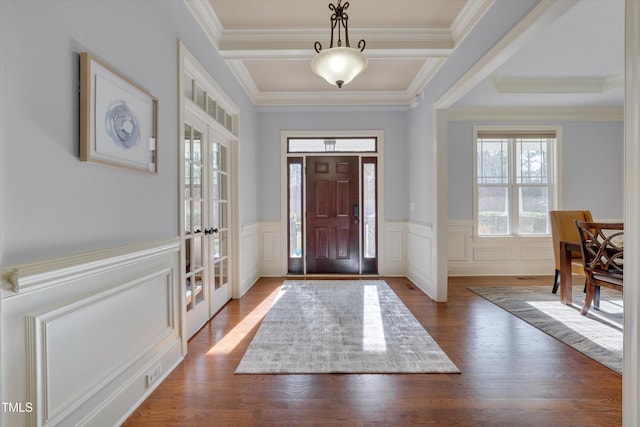 entrance foyer featuring a wainscoted wall, french doors, dark wood-type flooring, and crown molding