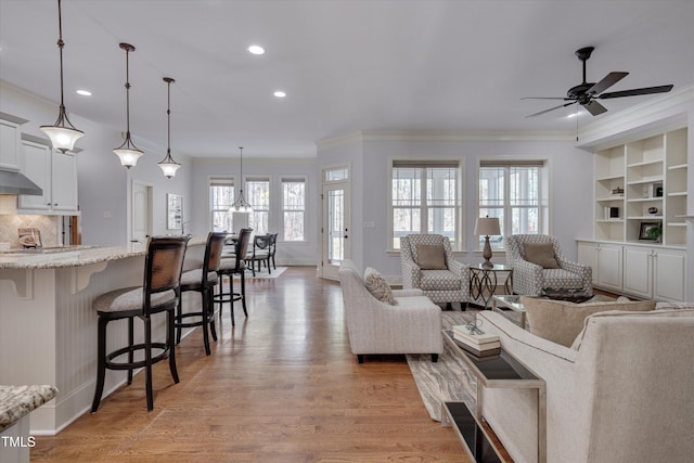 living room with recessed lighting, a ceiling fan, baseboards, light wood-style floors, and ornamental molding