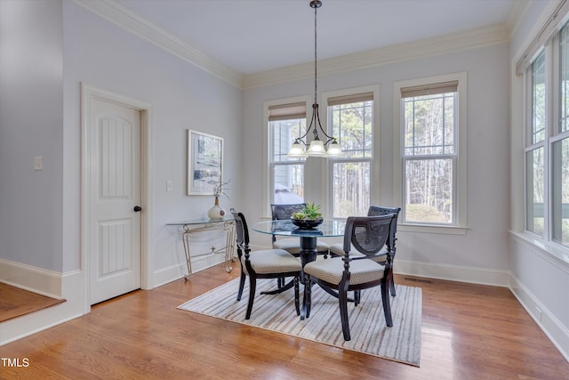 dining space featuring a wealth of natural light, crown molding, and wood finished floors