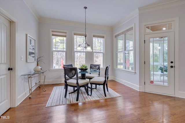 dining space featuring ornamental molding, baseboards, and wood finished floors