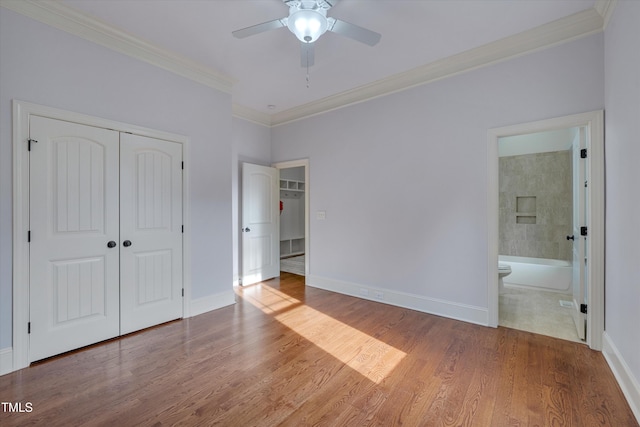 unfurnished bedroom featuring ornamental molding, a closet, baseboards, and wood finished floors