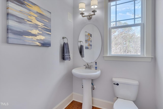 half bath featuring baseboards and toilet