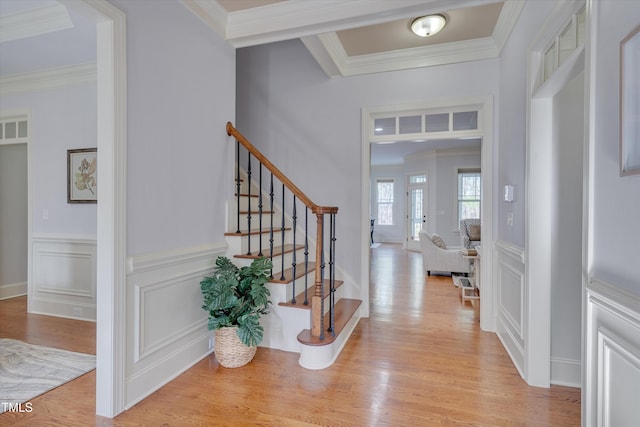 entryway with light wood-style floors, stairs, ornamental molding, and a decorative wall