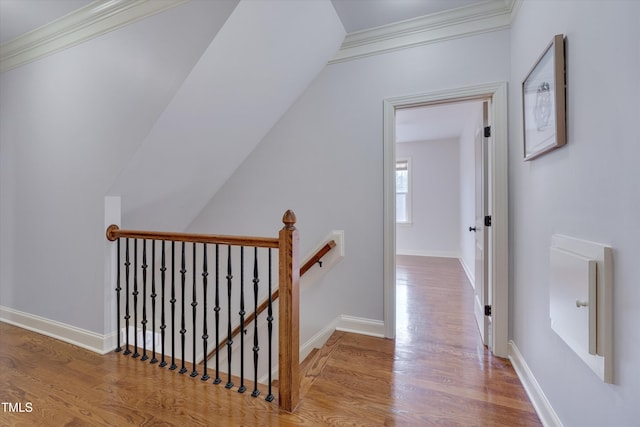 corridor with ornamental molding, baseboards, light wood-style flooring, and an upstairs landing