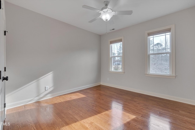 spare room with visible vents, ceiling fan, baseboards, and wood finished floors