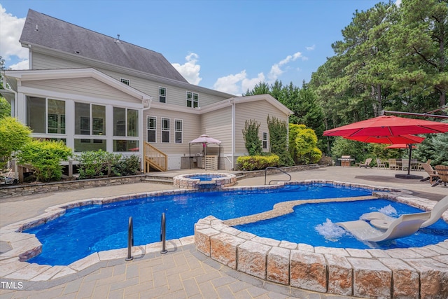 view of pool with a sunroom, a pool with connected hot tub, and a patio area