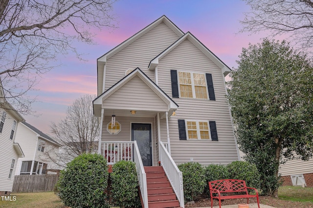 traditional-style home featuring a porch and fence