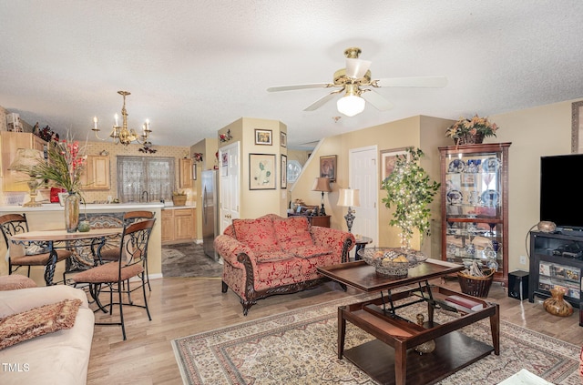 living area with light wood-style flooring, ceiling fan with notable chandelier, and a textured ceiling