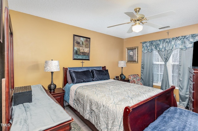 bedroom featuring visible vents, a textured ceiling, and ceiling fan