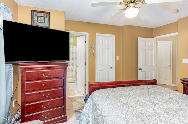 carpeted bedroom featuring a ceiling fan, ensuite bathroom, and a textured ceiling