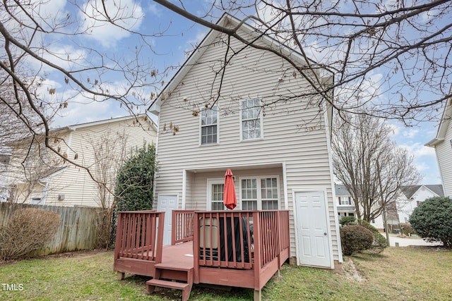 back of property with a deck, a yard, and fence