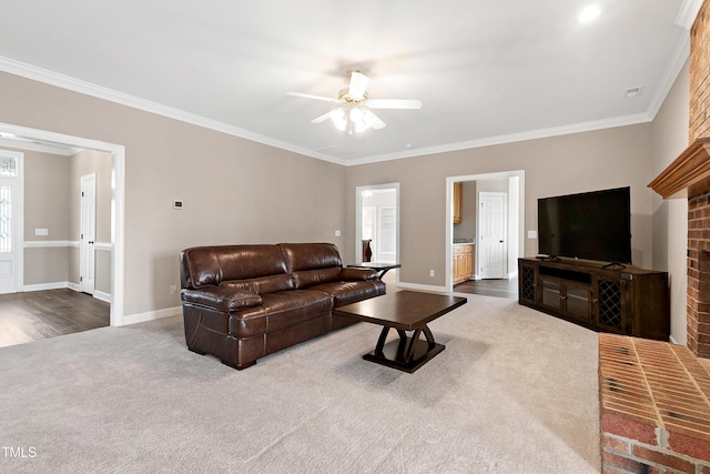 living area featuring dark colored carpet, ornamental molding, a ceiling fan, and baseboards