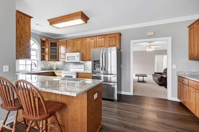 kitchen featuring white appliances, glass insert cabinets, light stone counters, and ornamental molding