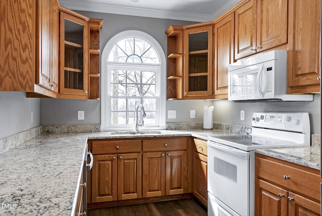 kitchen with brown cabinets, ornamental molding, glass insert cabinets, a sink, and white appliances