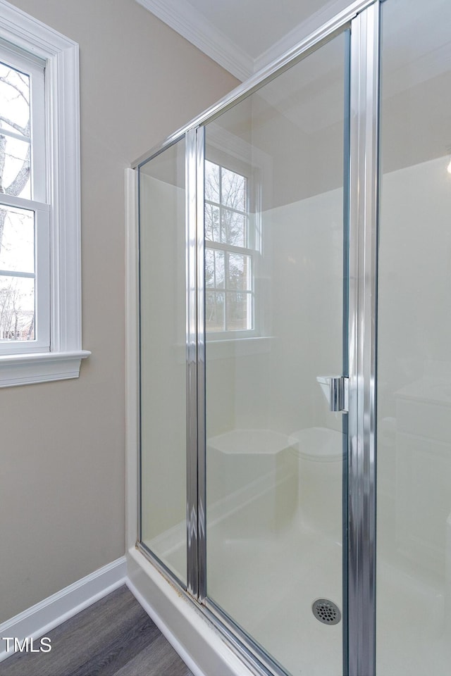 bathroom with ornamental molding, a shower stall, and baseboards