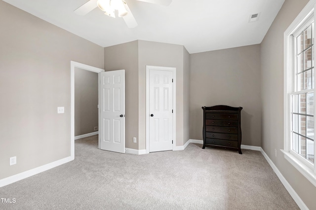 unfurnished bedroom featuring visible vents, ceiling fan, light carpet, and baseboards