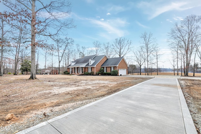 view of front facade with covered porch, brick siding, driveway, and an attached garage