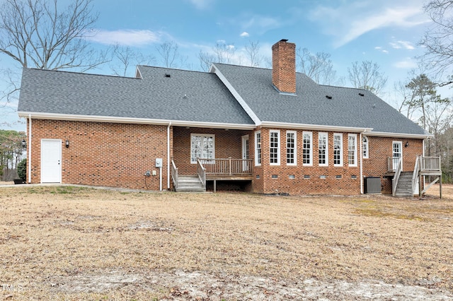 back of house with a deck, brick siding, a chimney, and roof with shingles