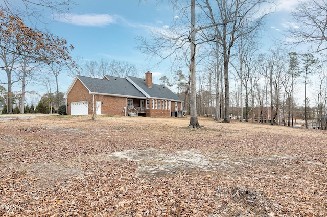 view of home's exterior with a garage, a chimney, a deck, and brick siding