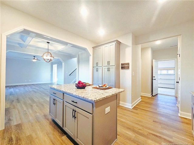 kitchen with coffered ceiling, a center island, light wood-type flooring, gray cabinetry, and hanging light fixtures