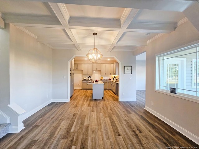 kitchen featuring wood-type flooring, pendant lighting, coffered ceiling, a center island, and an inviting chandelier