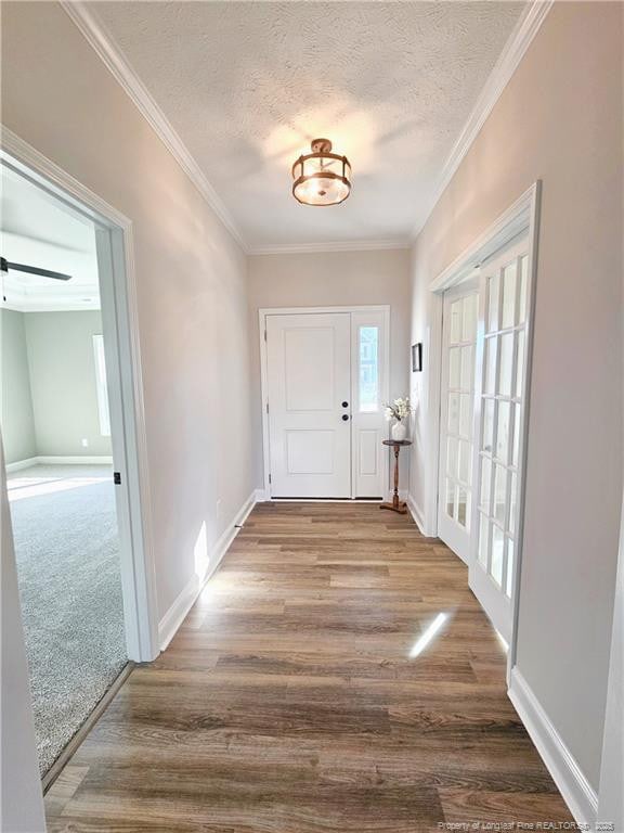 doorway featuring a textured ceiling, ornamental molding, and wood-type flooring