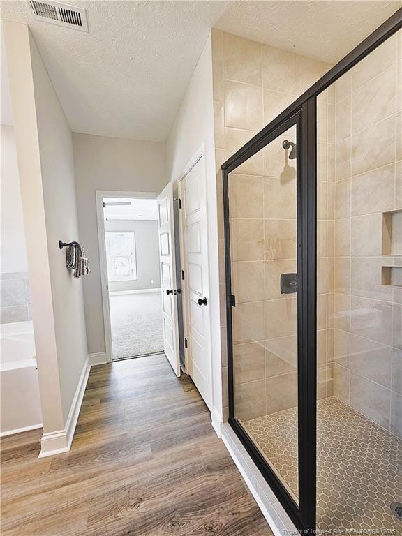 bathroom featuring a textured ceiling, a shower with shower door, and hardwood / wood-style floors