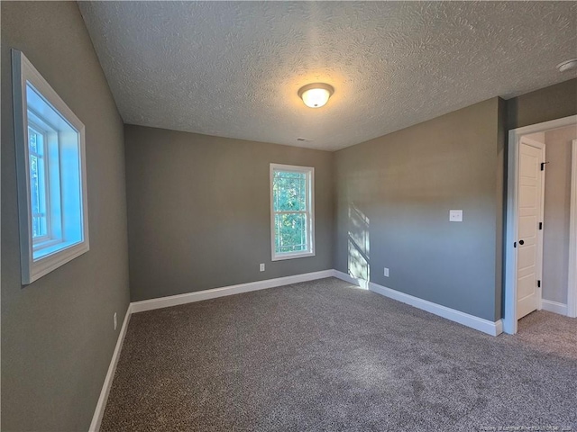 empty room with a textured ceiling and carpet flooring