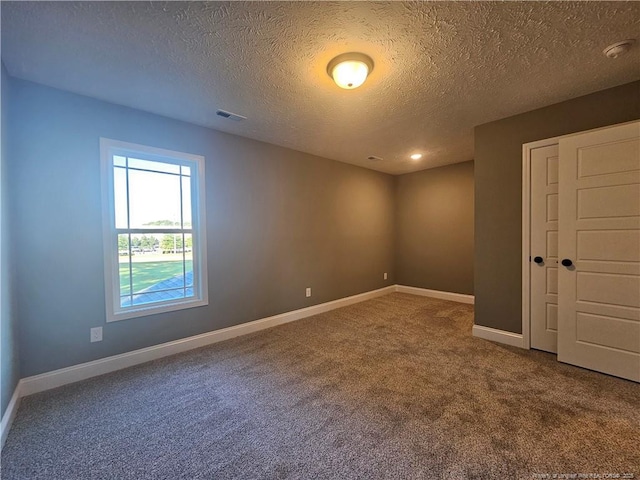 spare room featuring carpet and a textured ceiling