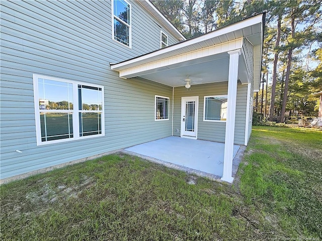 doorway to property featuring a lawn, ceiling fan, and a patio area