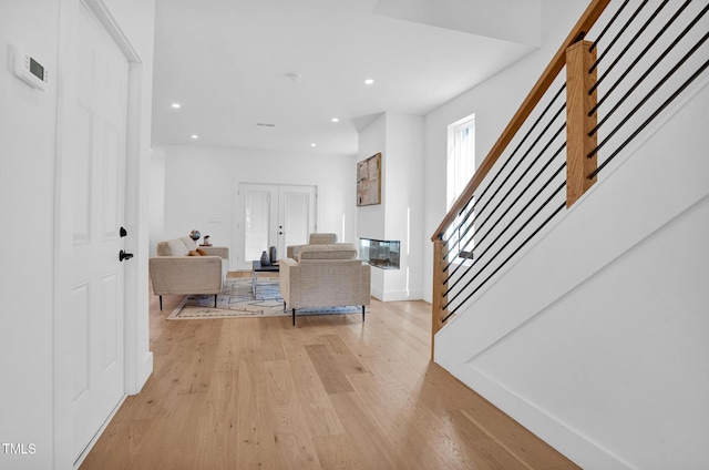 interior space featuring french doors, recessed lighting, light wood-type flooring, baseboards, and stairs