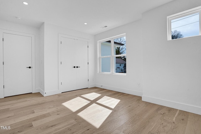 interior space featuring light wood-style floors, visible vents, multiple windows, and baseboards