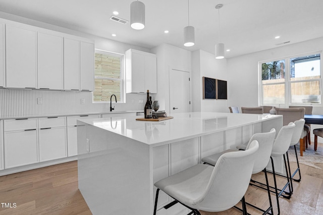 kitchen with white cabinets, pendant lighting, light countertops, and a center island