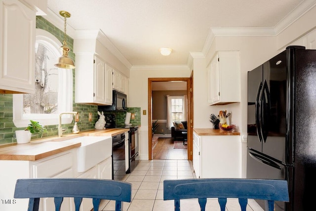 kitchen with white cabinets, decorative light fixtures, black appliances, and light tile patterned flooring