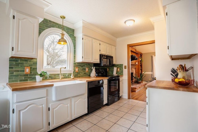 kitchen with decorative light fixtures, wooden counters, white cabinetry, a sink, and black appliances