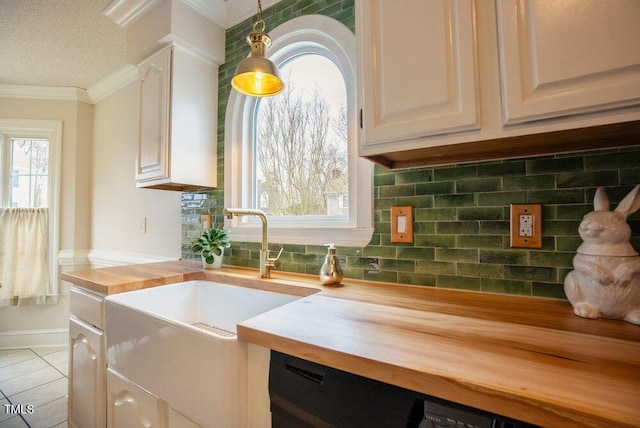 kitchen with light tile patterned floors, butcher block countertops, ornamental molding, hanging light fixtures, and backsplash