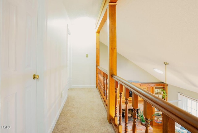 corridor with light carpet, baseboards, vaulted ceiling, and an upstairs landing