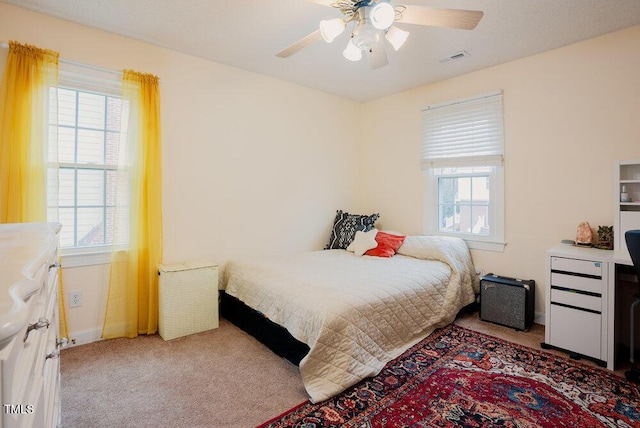 carpeted bedroom with a ceiling fan, visible vents, and baseboards