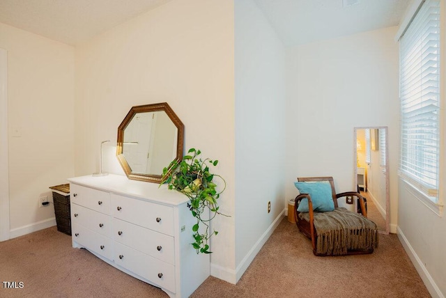 living area with baseboards and light colored carpet