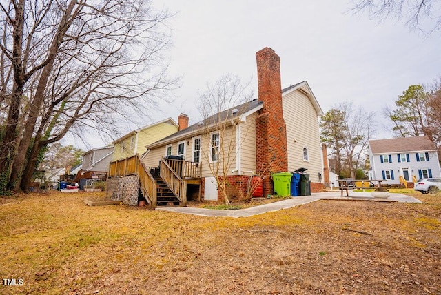 rear view of house featuring a yard, stairway, a wooden deck, a chimney, and a patio area