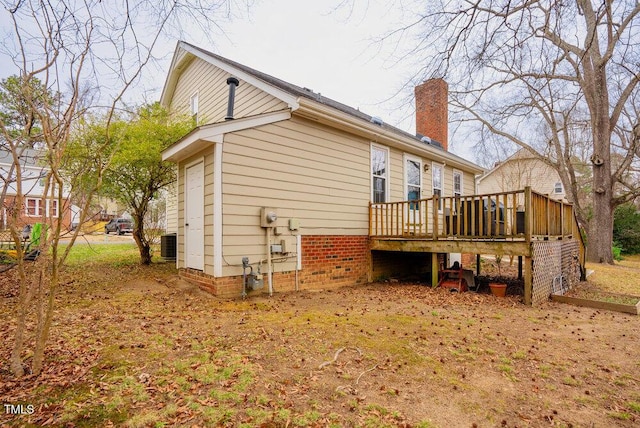 back of house with a chimney and a wooden deck