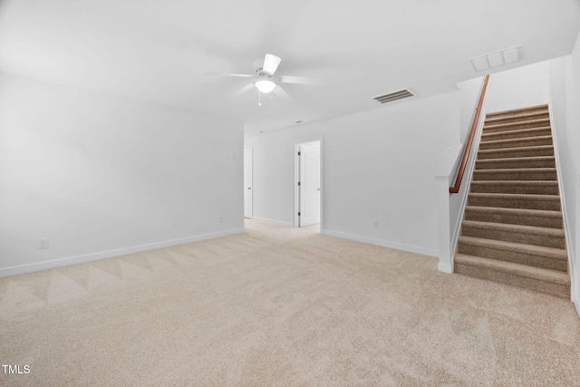 unfurnished living room with light colored carpet, visible vents, ceiling fan, baseboards, and stairs