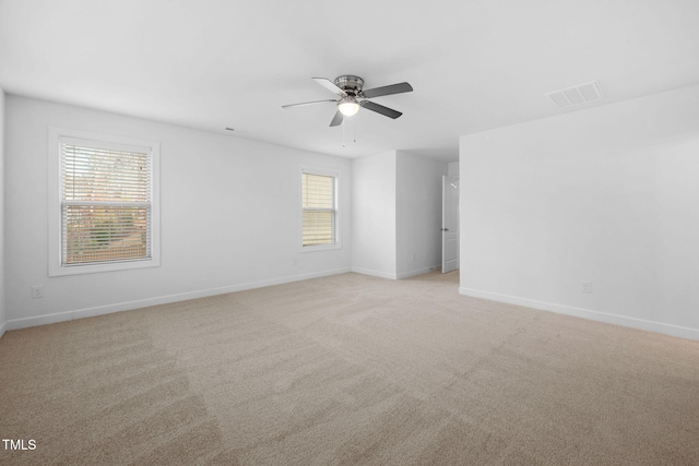 spare room featuring baseboards, a ceiling fan, visible vents, and light colored carpet