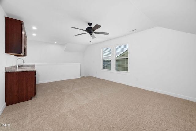 unfurnished living room featuring light carpet, baseboards, lofted ceiling, a sink, and recessed lighting